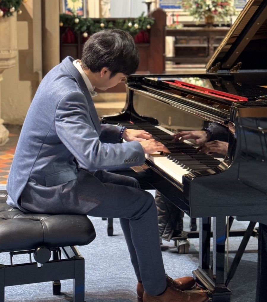 Eric Chung playing a grand piano at the Cadenza London 2025 student Christmas concert
